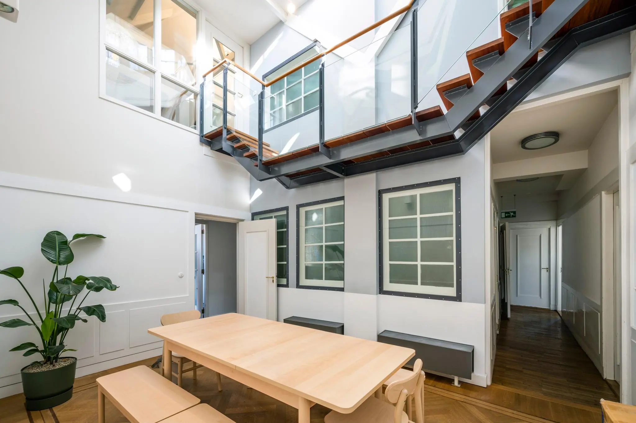 Lichte, moderne binnenruimte aan de Prof. Tulpstraat met houten tafel, plant en glazen loopbrug op de eerste verdieping.